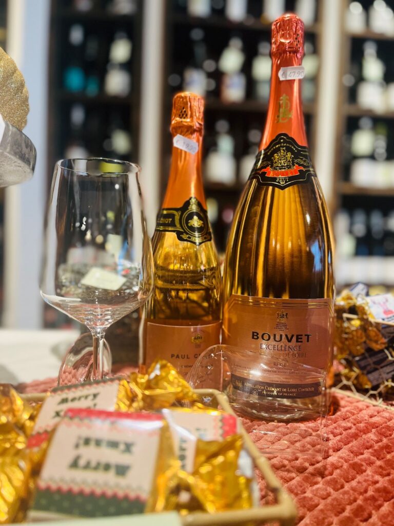 Zwei Flaschen Crémant rosé mit Glas und verpackten Pralinen